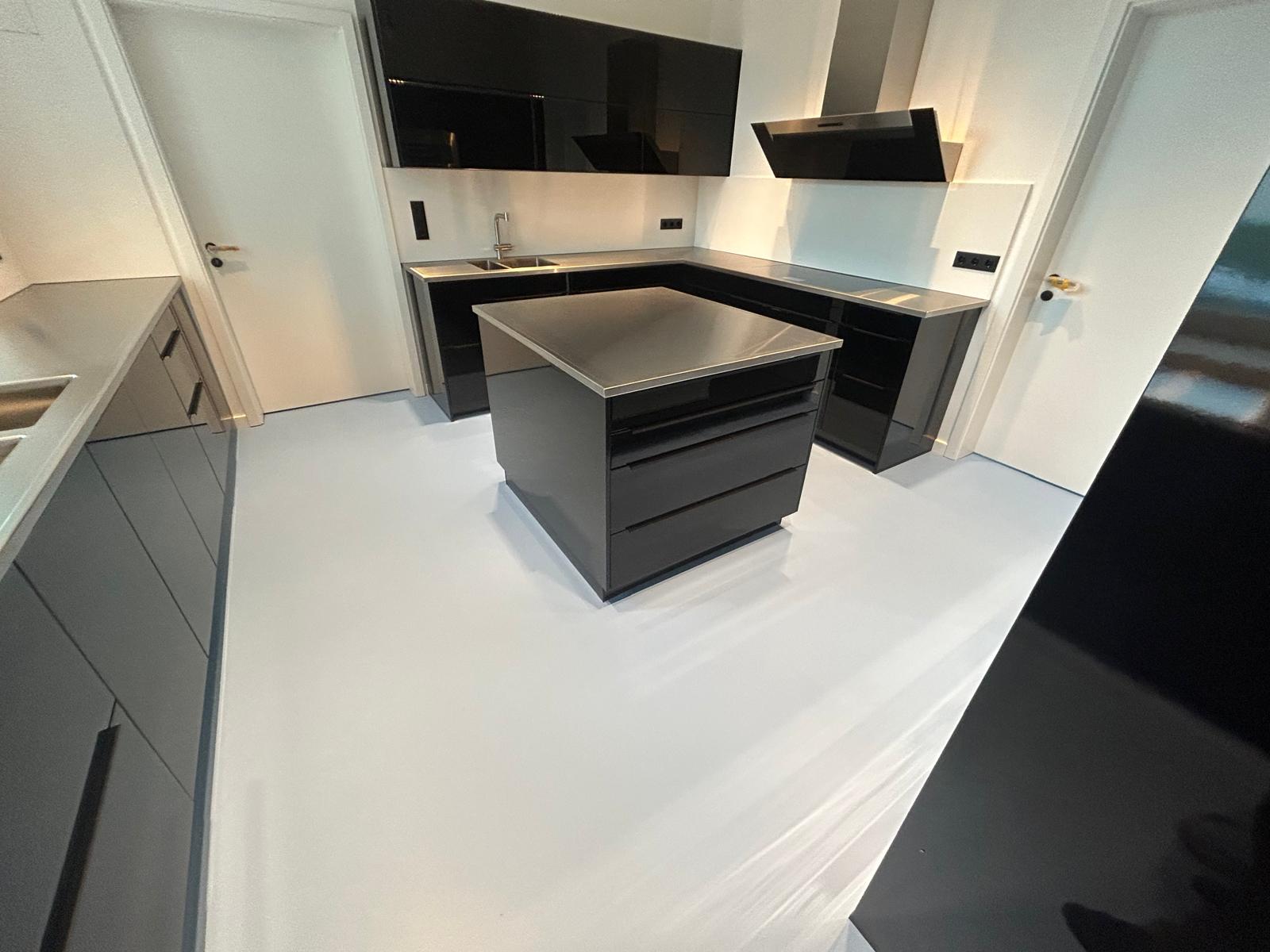 Eine moderne Küche für einen Haushalt mit maßgefertigten Edelstahloberflächen, modernen Küchengeräten und einer Kücheninsel