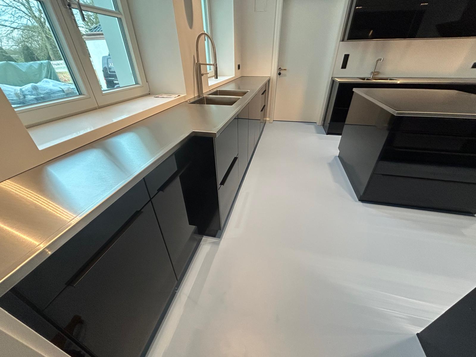 Eine moderne Küche für einen Haushalt mit maßgefertigten Edelstahloberflächen, modernen Küchengeräten und einer Kücheninsel