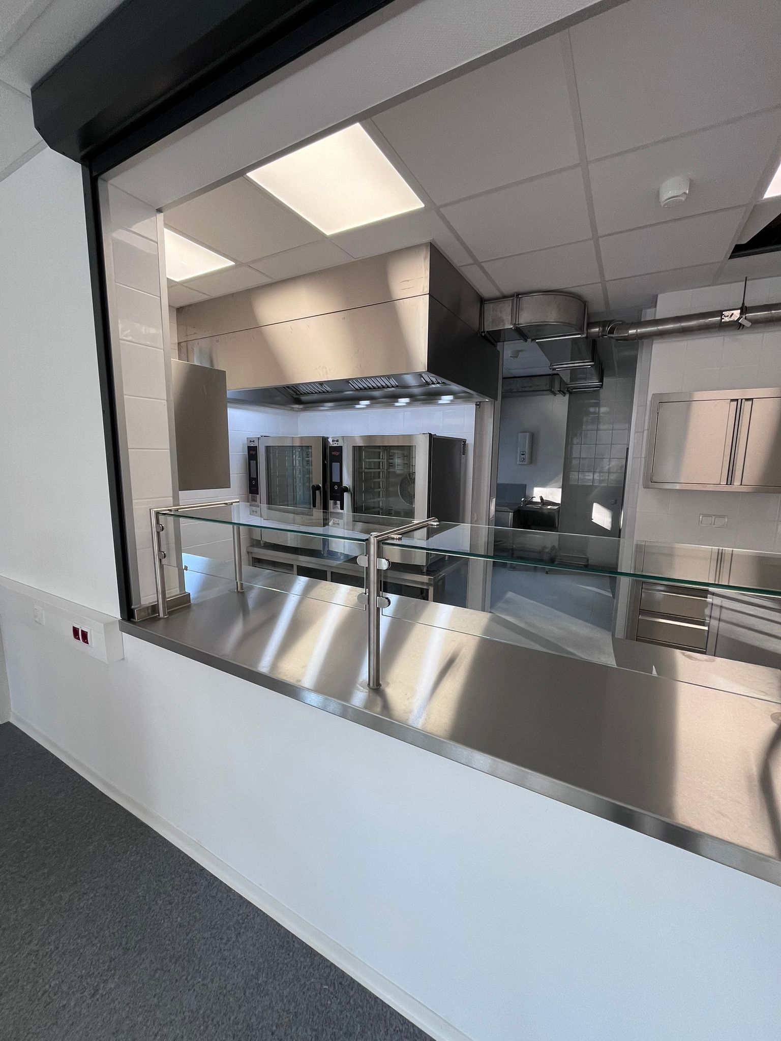 Eine von TIMMER gebaute Regenerierküche in einem Containerbau mit Edelstahltheken, einer Ausgabe und professionellen Großküchengeräten